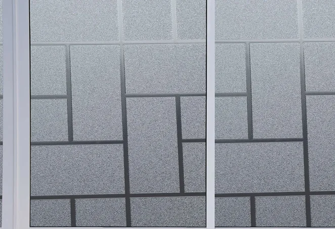 Close-up of decorative frosted window film with a geometric rectangular pattern, applied to glass panels for added privacy and style.